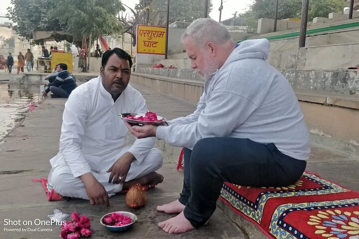 A priest performs a pooja with a visitor beside Pushkar Lake
